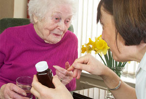 Elderly woman talking to nurse with pills.
