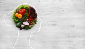 Fresh vegetables pictured in outline of womans head symbolizing brain health and nutrition