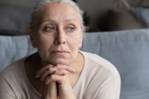 Head shot of older adult woman looking out into the distance, look of worry and stress on her face