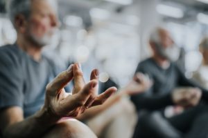 Close up of man's hand during Yoga meditation exercises in a health club blurred background