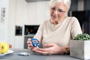 Older adult woman with glucometer checking blood sugar level at home
