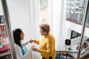 Nurse supporting senior patient walking or moving up the stairs at home
