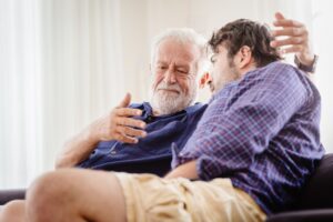 older man and adult son sit at home having serious discussion
