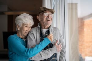 Senior couple looking through the window at home