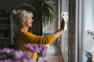 Mature woman cleaning windows in her home