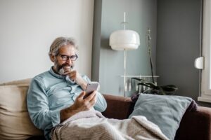 mature man in his modern apartment using a mobile phone while sitting on sofa