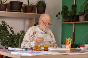 Senior Man with dementia is drawing on paper at home