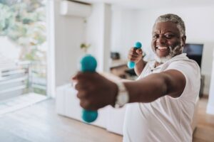 Elderly man exercising at home with dumbbell physiotherapy